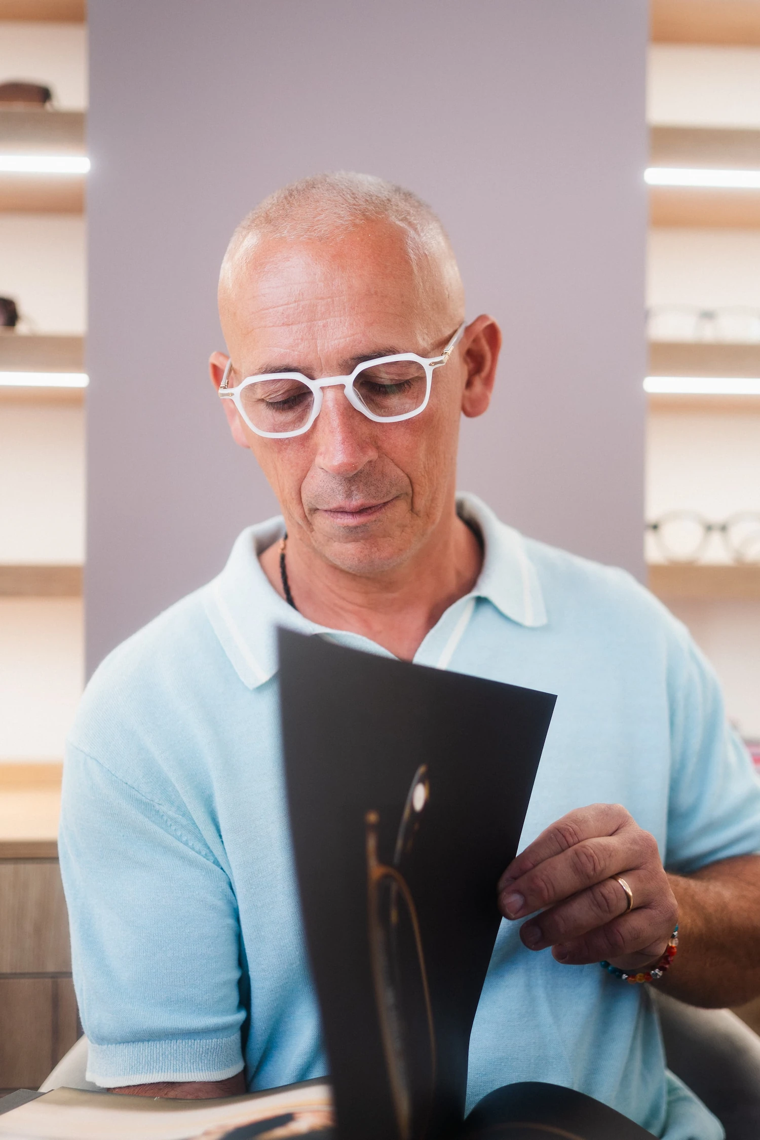 Uomo che legge un catalogo indossando occhiali da vista bianchi dalla forma esagonale