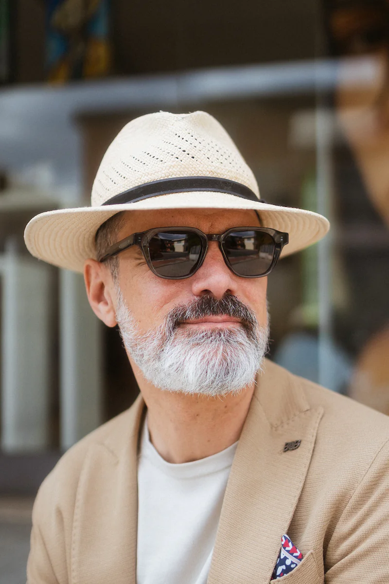 Ritratto street style con cappellino nero e grandi occhiali da vista neri spessi.